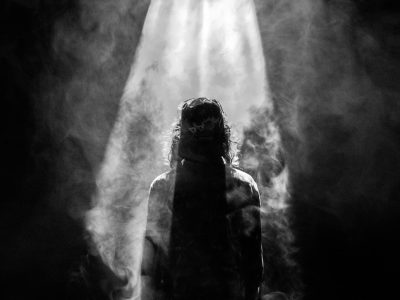 photograph of person facing opposite in smoky spotlight