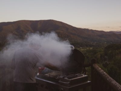 man barbecuing beside brown fence