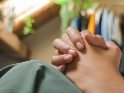 a person holding their hand in front of a rack of shirts