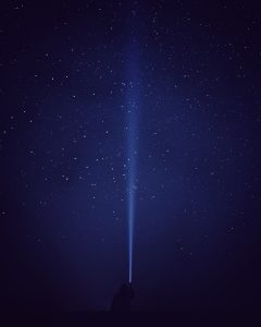 silhouette of person with flash light under starry night
