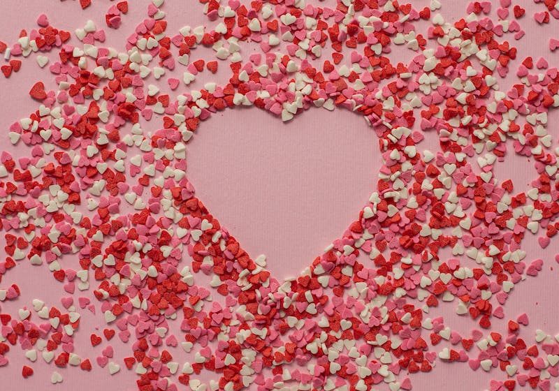 Paper hearts scattered on pink background